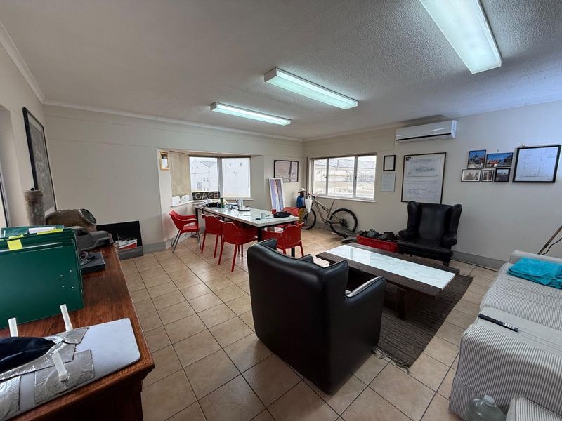 Spacious office area featuring tiled flooring, fluorescent lighting, and a wall-mounted split-system air conditioner, providing a functional workspace environment.