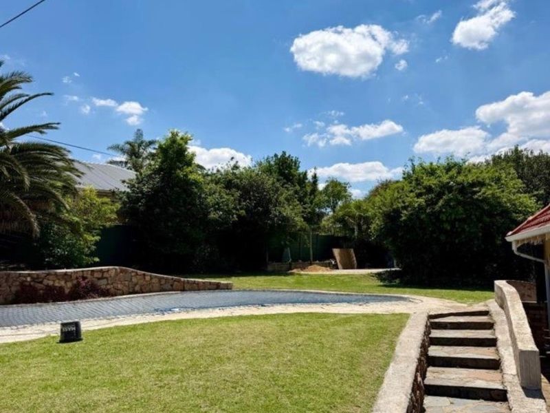 Outdoor pool area featuring a swimming pool with stone retaining walls and stone steps leading to the garden.
