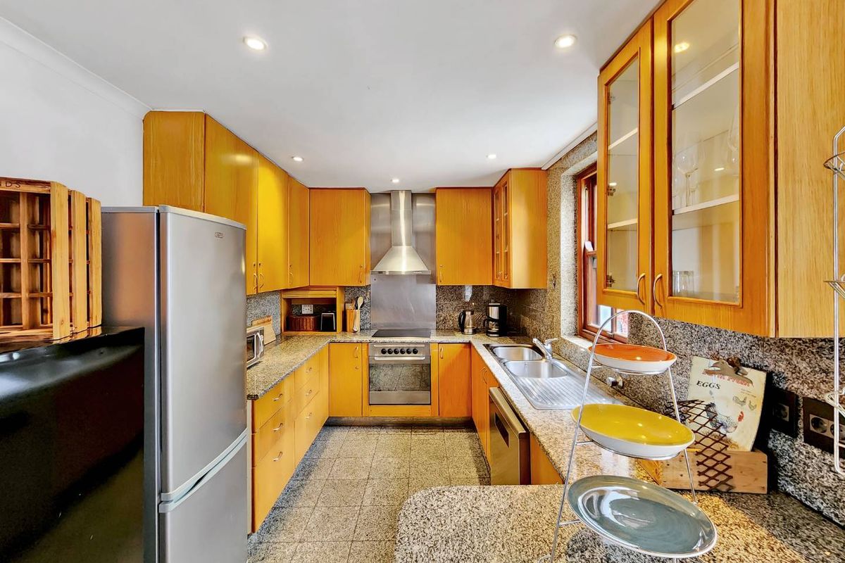 A functional kitchen featuring wooden cabinetry, granite countertops, stainless steel appliances, and recessed lighting, offering a practical layout for meal preparation.