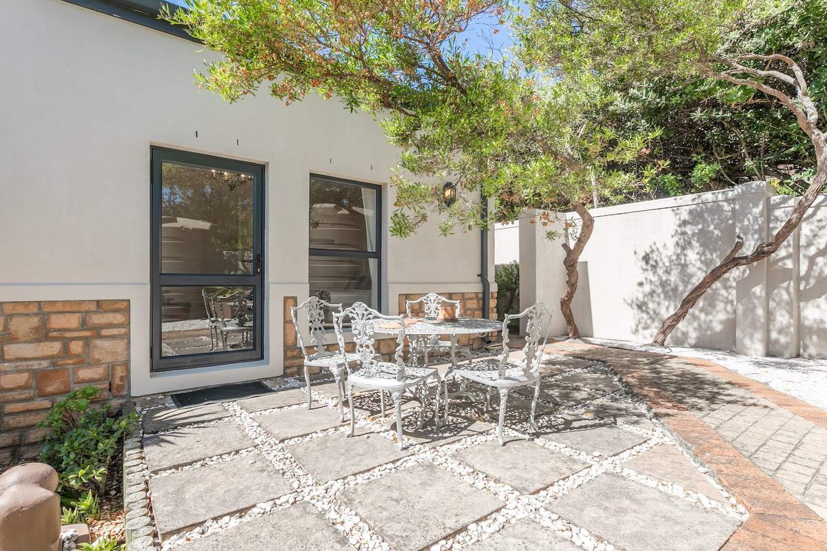 A private rear patio area featuring stone paving, a low-maintenance garden border, and direct access to the home through glass doors.