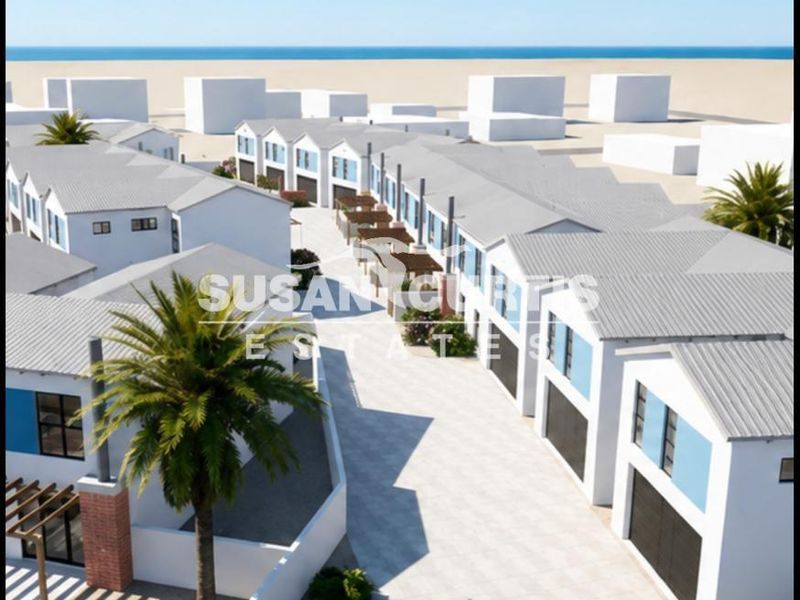 Aerial view of a modern townhouse development featuring uniform architectural design, paved driveways, and proximity to the coastline.