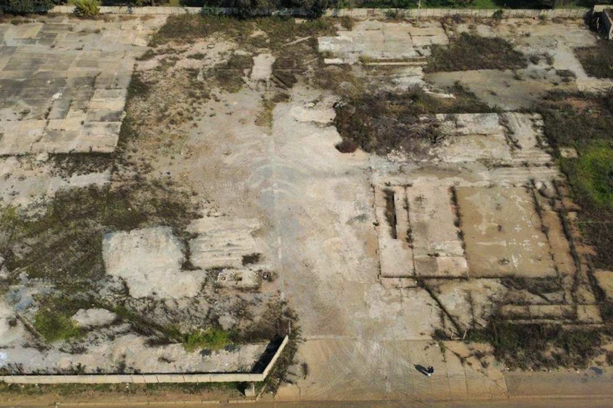 Aerial view of a vacant commercial land plot featuring existing concrete foundations and perimeter fencing, suitable for redevelopment.