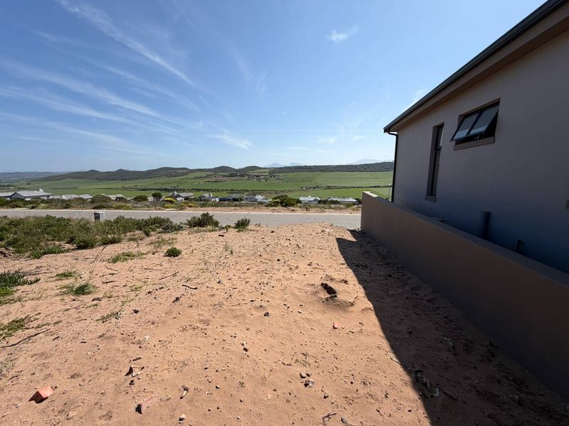 A view of the surrounding landscape and residential area from the side of a property with a retaining wall and modern window.