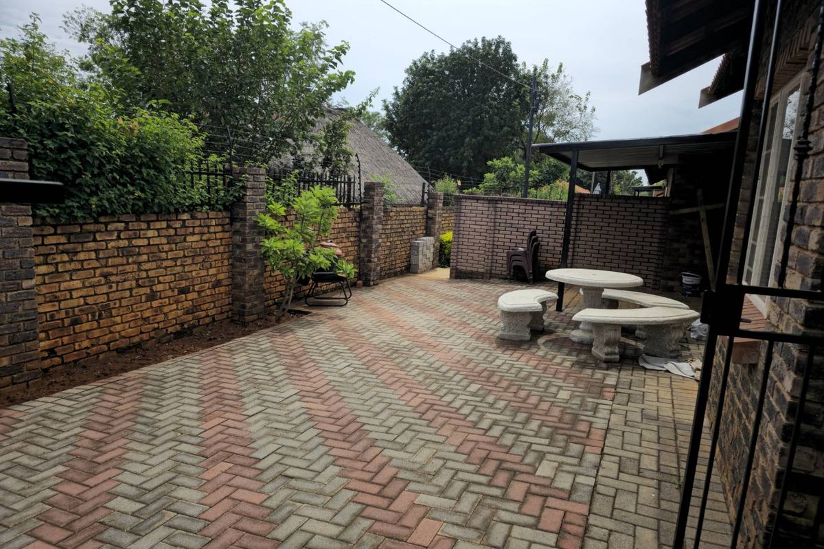A paved rear courtyard area featuring face-brick boundary walls, a covered patio section, and established perimeter fencing.