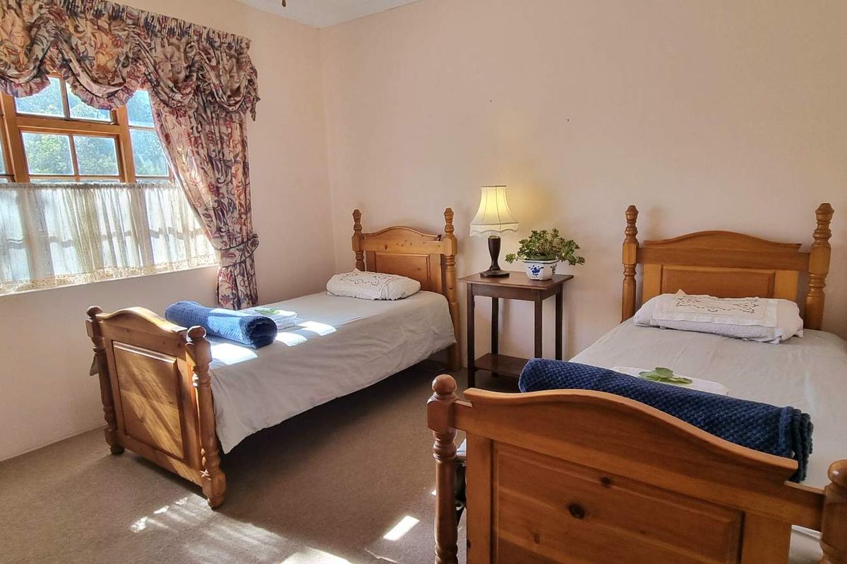 A bedroom featuring carpeted flooring and a window with traditional curtains, providing a functional and comfortable sleeping space.