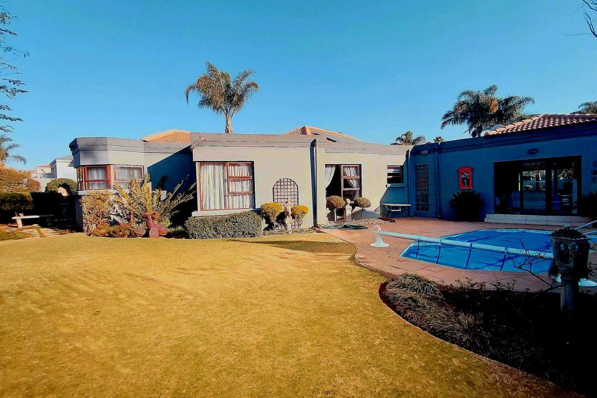 Rear view of the property featuring a well-maintained garden, a swimming pool with a paved deck, and direct access to the home via sliding doors.