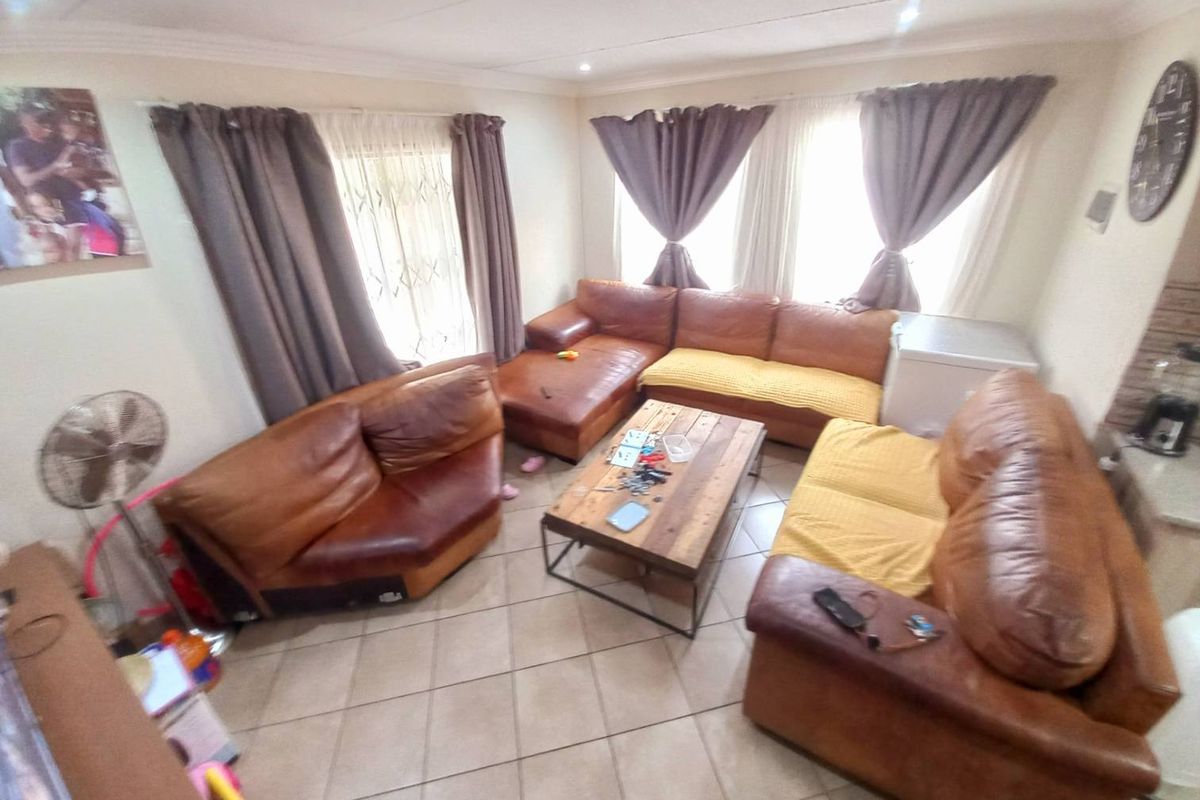 A spacious living room featuring tiled flooring and large windows, providing a comfortable area for relaxation and family gatherings.