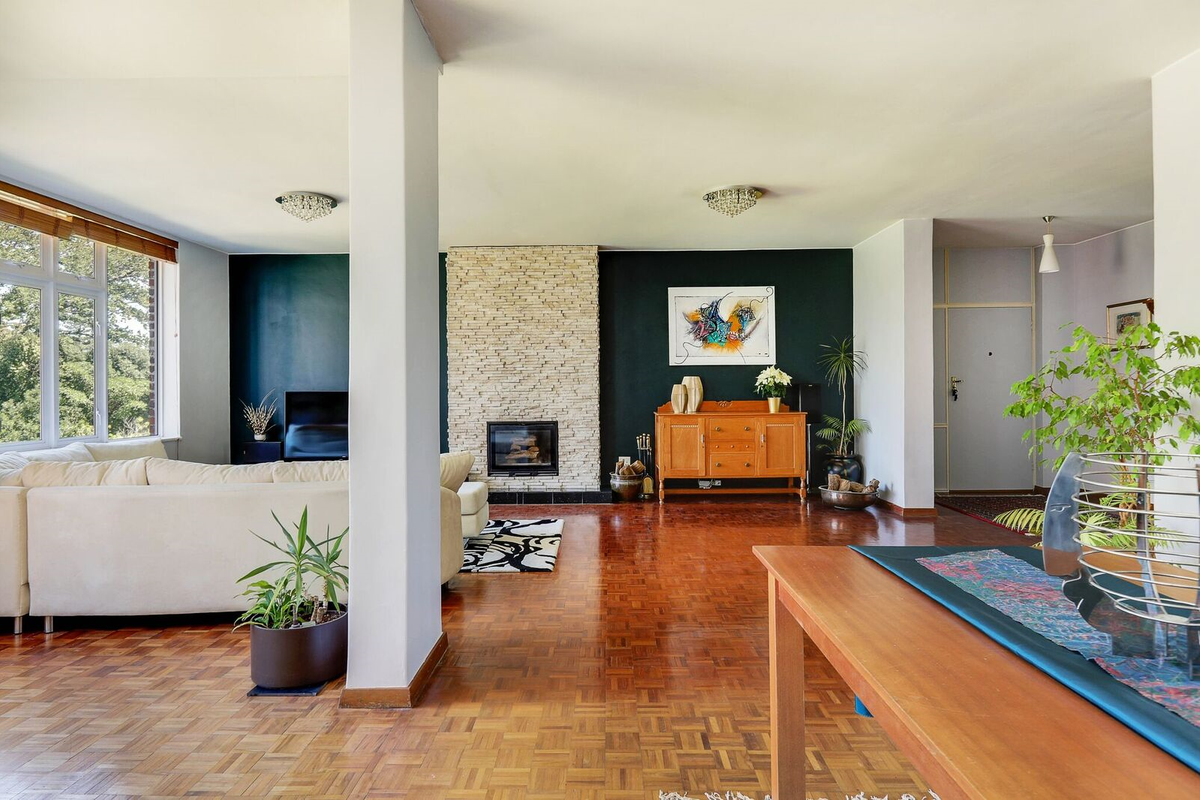 Spacious living area featuring classic parquet flooring, a striking stone-clad fireplace, and an open-plan layout with abundant natural light.