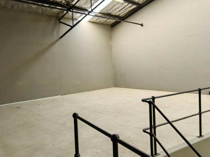 An open-plan industrial utility space featuring a raised concrete platform with safety railings, exposed steel roof trusses, and natural light from skylights.