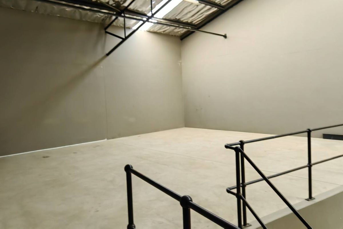 An open-plan industrial utility space featuring a raised concrete platform with safety railings, exposed steel roof trusses, and natural light from skylights.