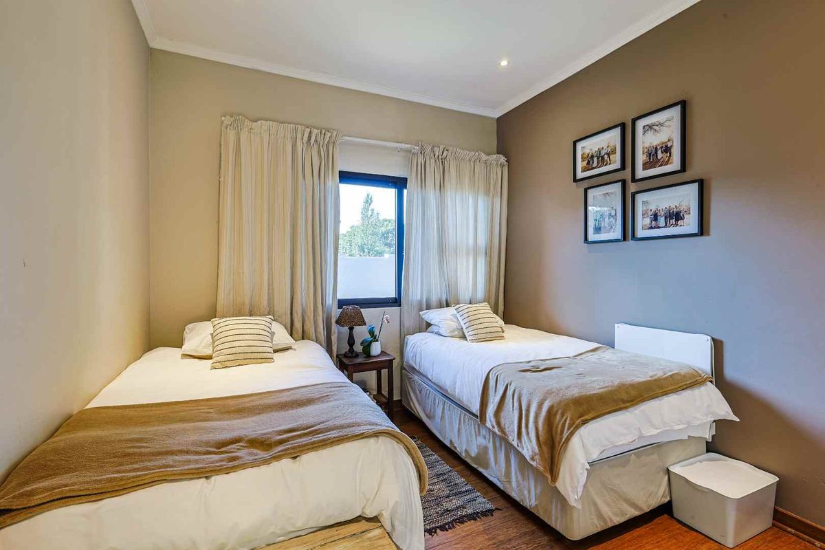 A well-maintained bedroom featuring laminate flooring, neutral wall tones, and recessed downlighting, providing a comfortable and functional sleeping space.