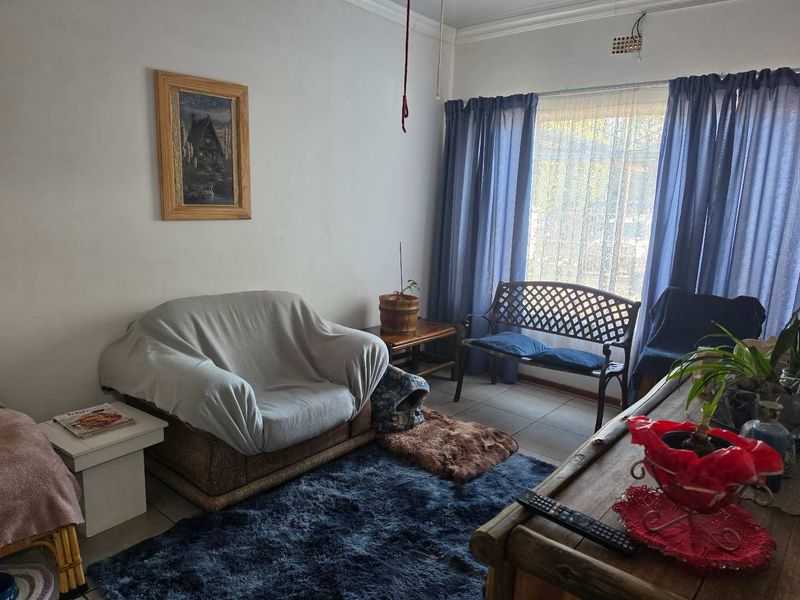 A living room area featuring tiled flooring and a large window, currently requiring minor electrical repairs to the ceiling fixture.