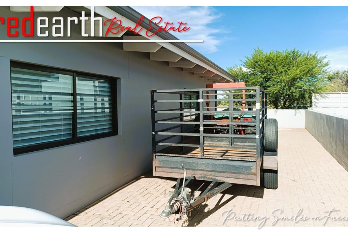 A view of the side exterior area featuring paved flooring, modern grey wall finish, and black-framed windows.