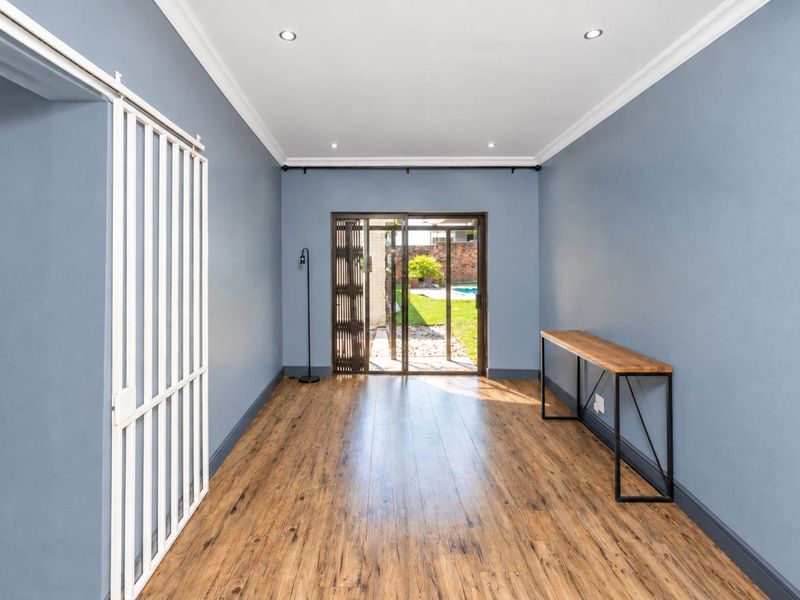 A bright, empty living area featuring wood-look laminate flooring, recessed lighting, and a sliding glass door providing direct access to the rear garden.