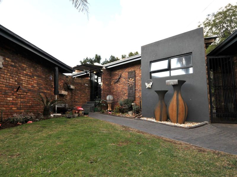 Front entrance area featuring a brick facade, paved walkway, and landscaped garden with modern architectural accents.