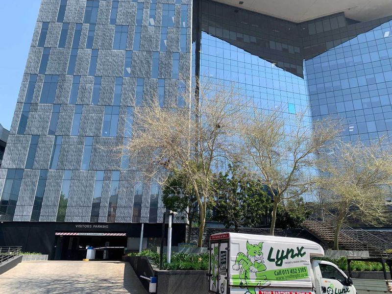 Modern commercial office building featuring a glass curtain wall facade and a dedicated visitors' parking entrance.