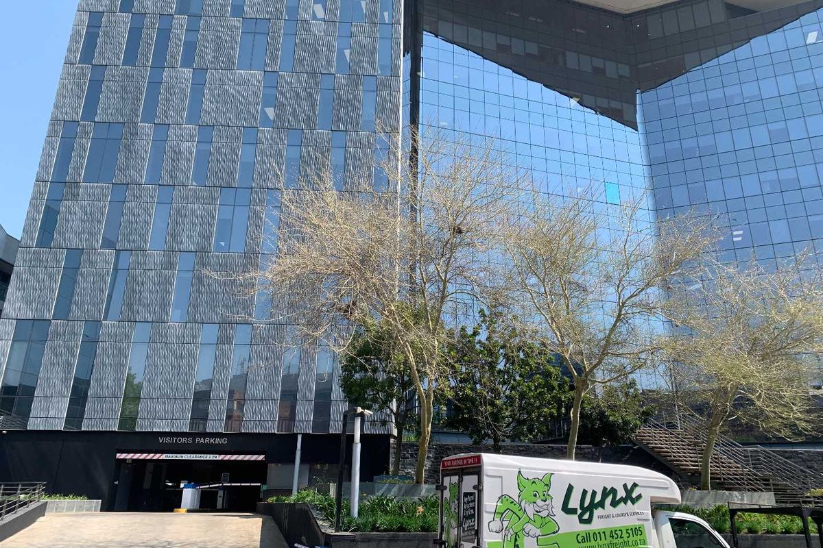 Modern commercial office building featuring a glass curtain wall facade and a dedicated visitors' parking entrance.