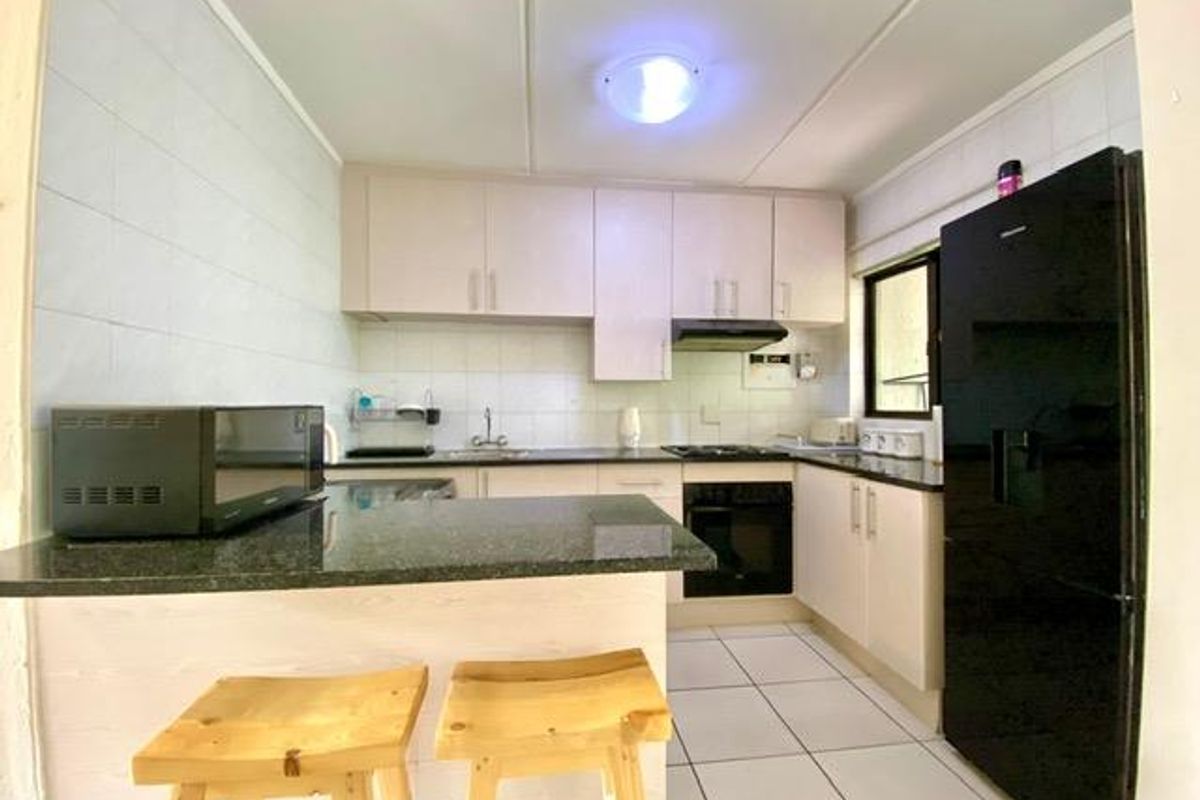 A functional kitchen featuring granite countertops, built-in cabinetry, a breakfast bar, and integrated oven with hob.