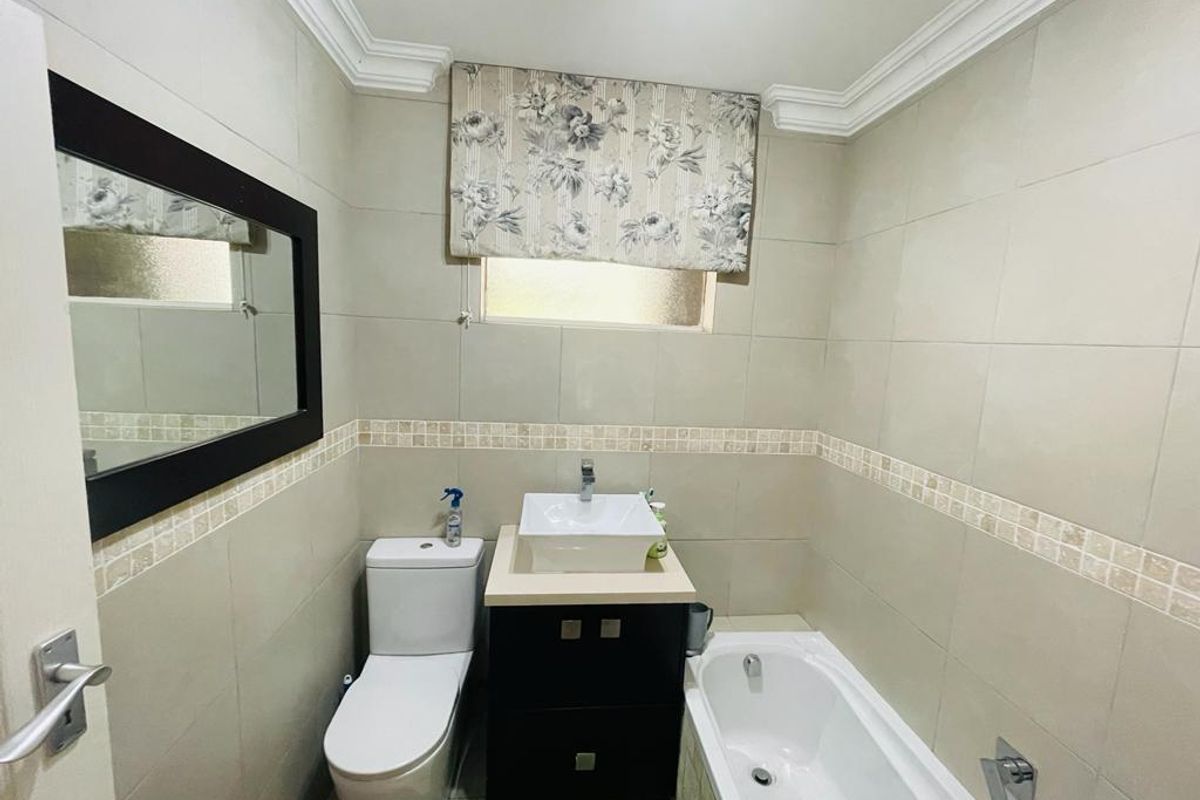 A functional bathroom featuring a vessel sink vanity, a standard toilet, and a bathtub with neutral wall tiling and crown molding.