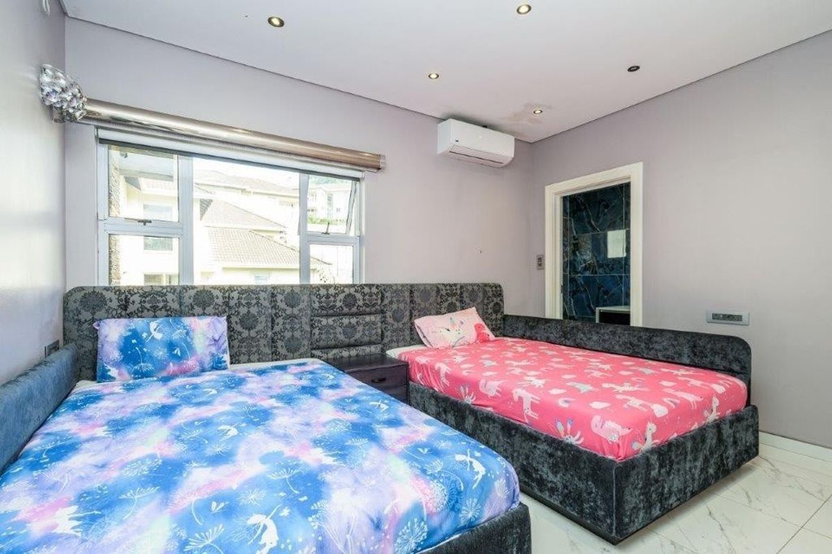 A bedroom featuring tiled flooring, recessed downlighting, and a wall-mounted air conditioning unit, with visible water staining on the ceiling.