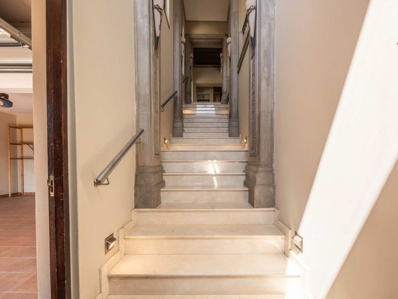 A well-lit interior hallway featuring a stone staircase with integrated step lighting and decorative stone architraves.