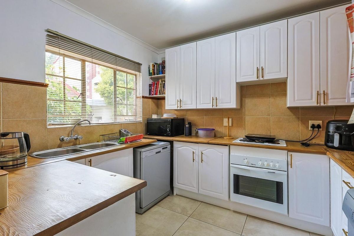 Functional kitchen featuring white cabinetry, wood-look laminate countertops, a double basin sink, and a built-in oven with a hob.