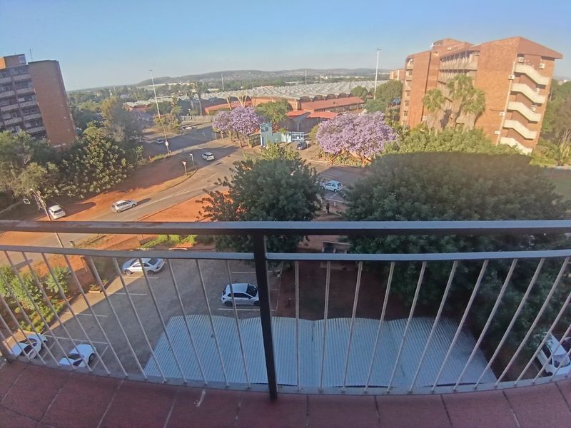 Elevated view from a balcony overlooking the surrounding neighborhood, parking area, and local street infrastructure.