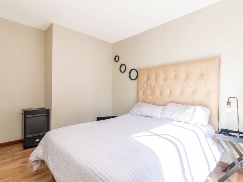A bedroom featuring laminate flooring and neutral wall finishes, providing a functional and comfortable sleeping space.
