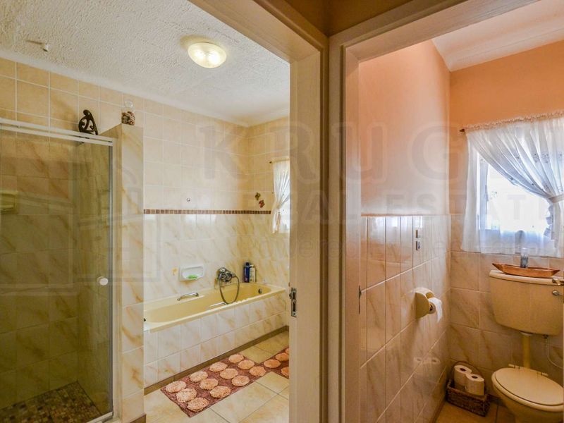 A functional bathroom featuring a separate shower enclosure, built-in bathtub, and a private toilet area with tiled finishes throughout.