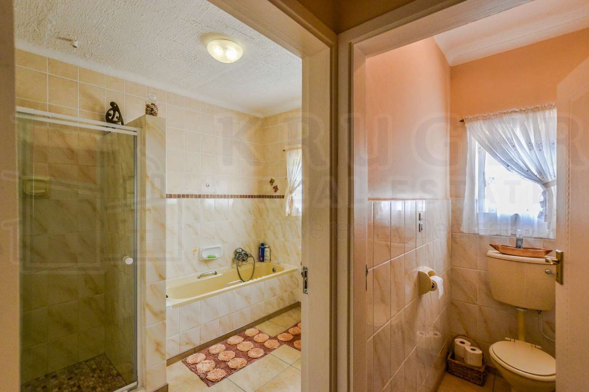 A functional bathroom featuring a separate shower enclosure, built-in bathtub, and a private toilet area with tiled finishes throughout.