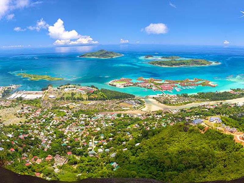 A panoramic aerial view showcasing the coastal landscape, turquoise waters, islands, and surrounding residential development.
