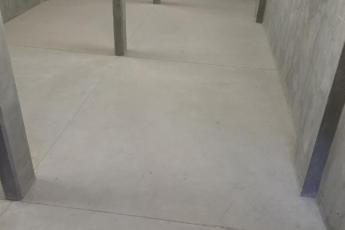 An expansive, unfinished industrial utility space featuring raw concrete flooring, walls, and structural support columns, suitable for storage or workshop conversion.
