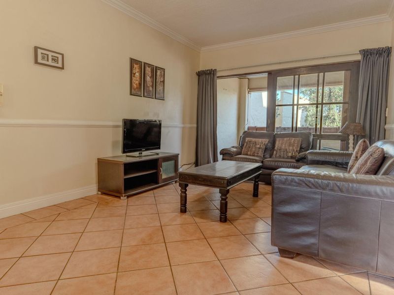 A living room featuring ceramic tile flooring, crown molding, and a sliding glass door providing access to an outdoor area.