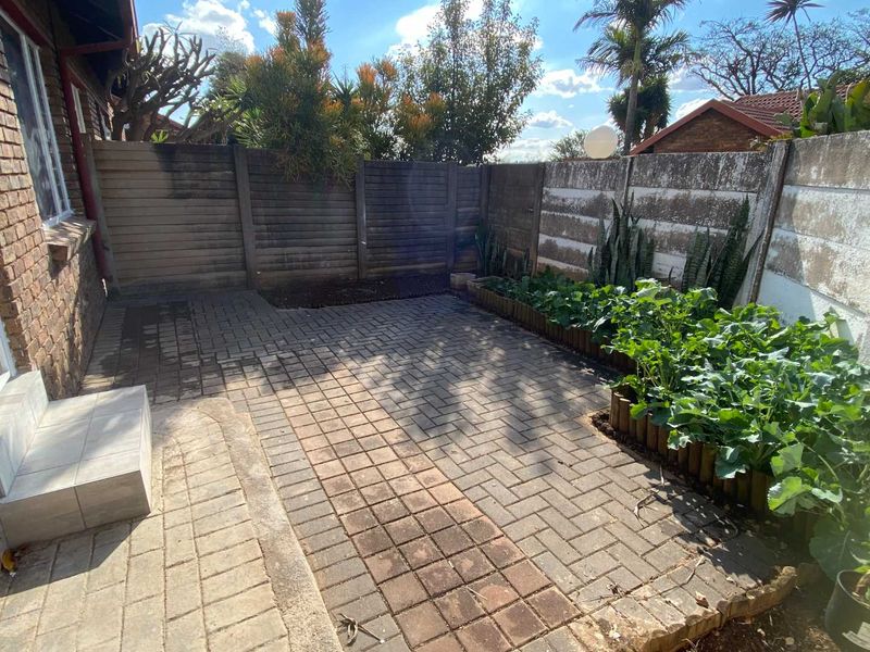 A private rear courtyard featuring paved flooring, a raised garden bed, and a combination of precast concrete and timber boundary fencing.