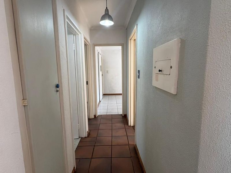A functional hallway featuring tiled flooring, a pendant light fixture, and built-in storage, providing access to multiple rooms within the home.