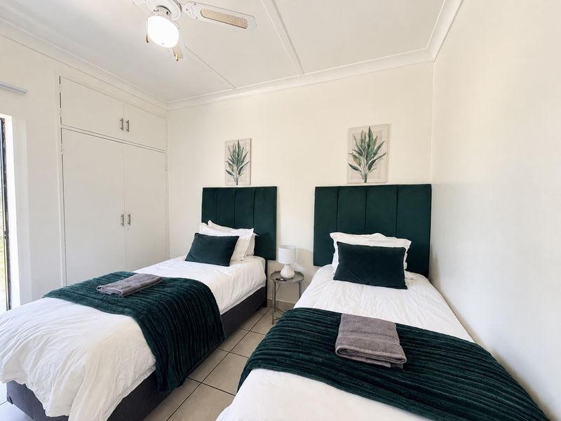 A well-maintained bedroom featuring built-in cupboards, tiled flooring, and a ceiling fan, offering a clean and functional living space.