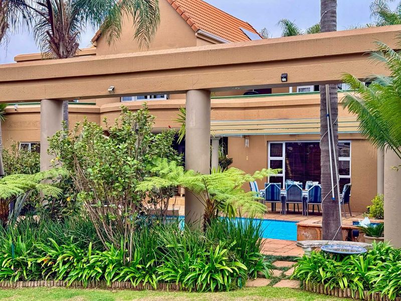 Rear view of the property featuring a swimming pool, paved patio area, and a large pergola structure set against the main house elevation.