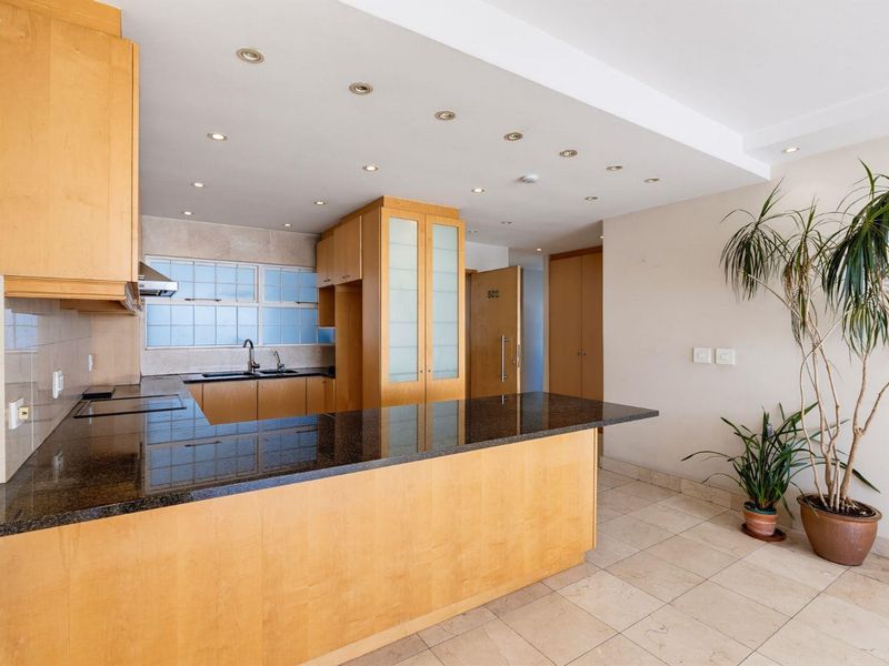 A well-maintained kitchen featuring light wood cabinetry, dark granite countertops, a double sink, and recessed lighting, offering a clean and functional workspace.