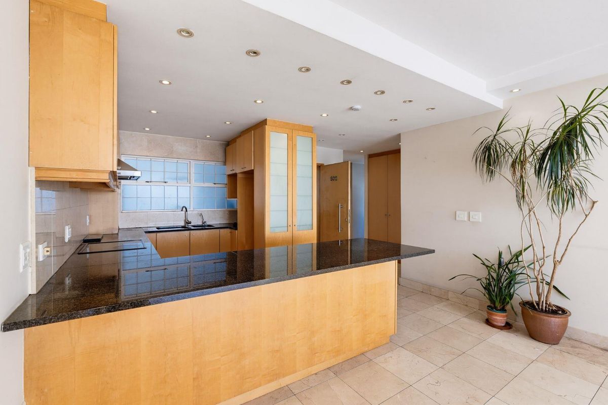 A well-maintained kitchen featuring light wood cabinetry, dark granite countertops, a double sink, and recessed lighting, offering a clean and functional workspace.