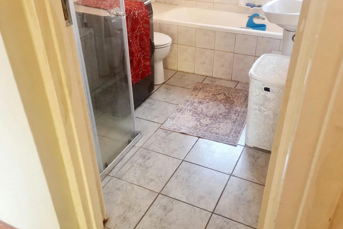 A functional bathroom featuring a bathtub, pedestal basin, and a separate shower enclosure with tiled finishes throughout.