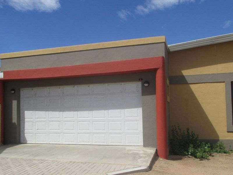 Exterior view of a single-car garage featuring a white sectional door, concrete driveway, and painted masonry facade.