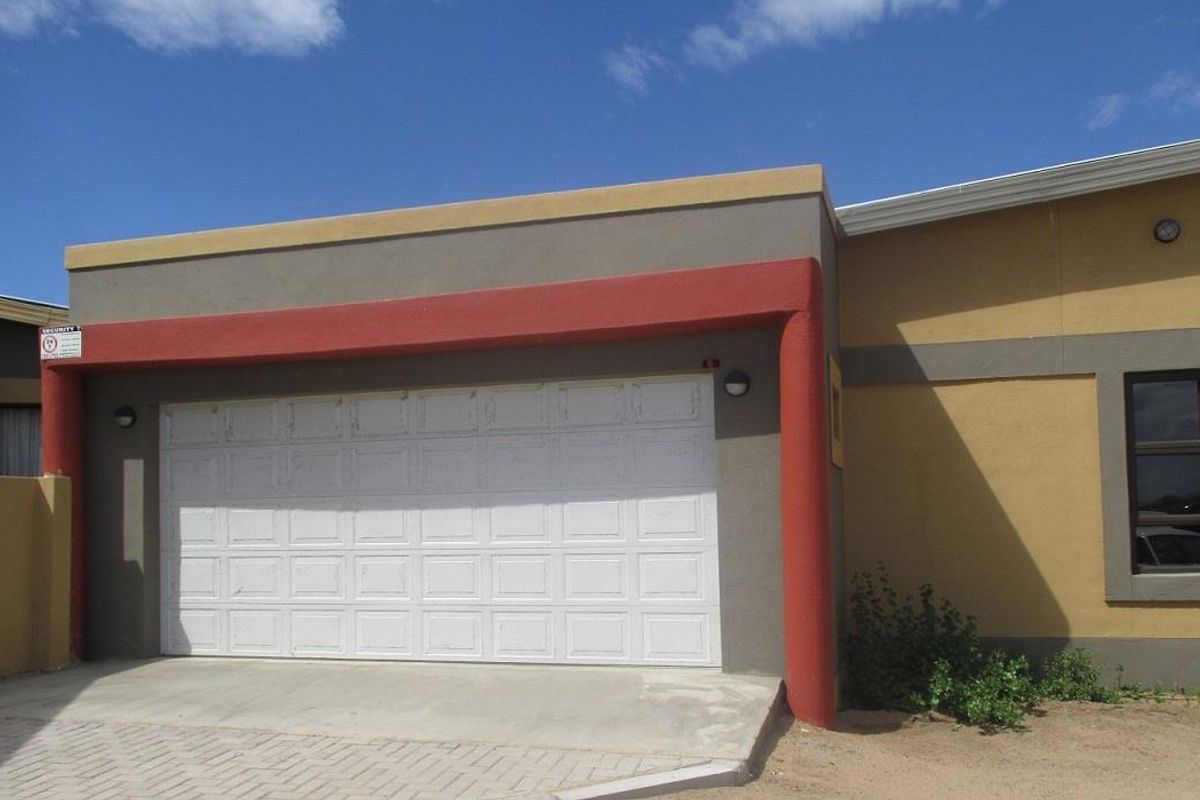 Exterior view of a single-car garage featuring a white sectional door, concrete driveway, and painted masonry facade.