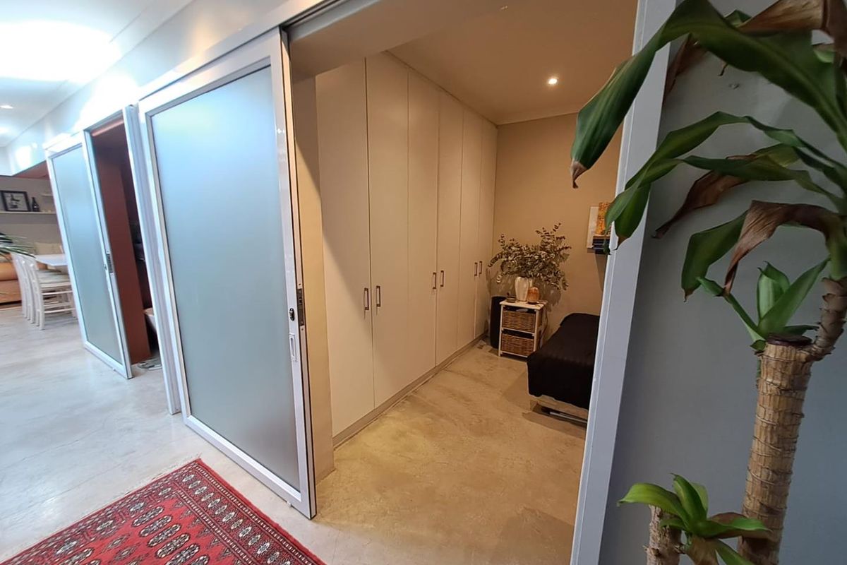 A bedroom featuring built-in floor-to-ceiling cabinetry and a sliding frosted glass door, providing a clean and modern storage solution.