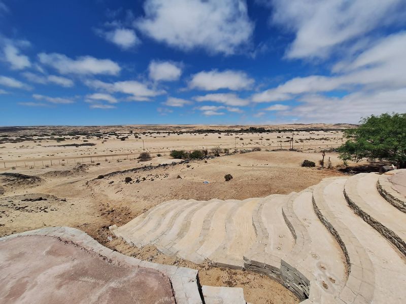 Expansive landscape view overlooking arid terrain with tiered stone terracing and retaining walls in the foreground.