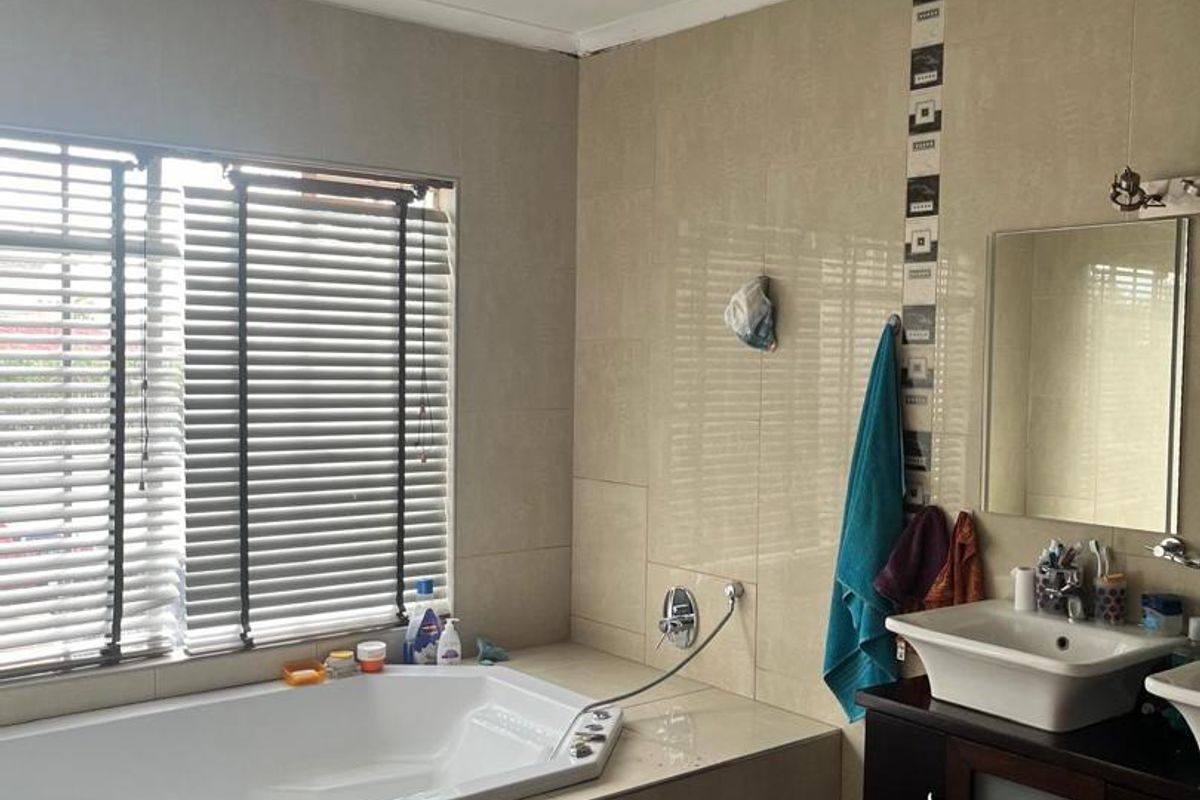 A functional bathroom featuring a built-in bathtub, vanity cabinet with basin, and tiled walls and flooring.