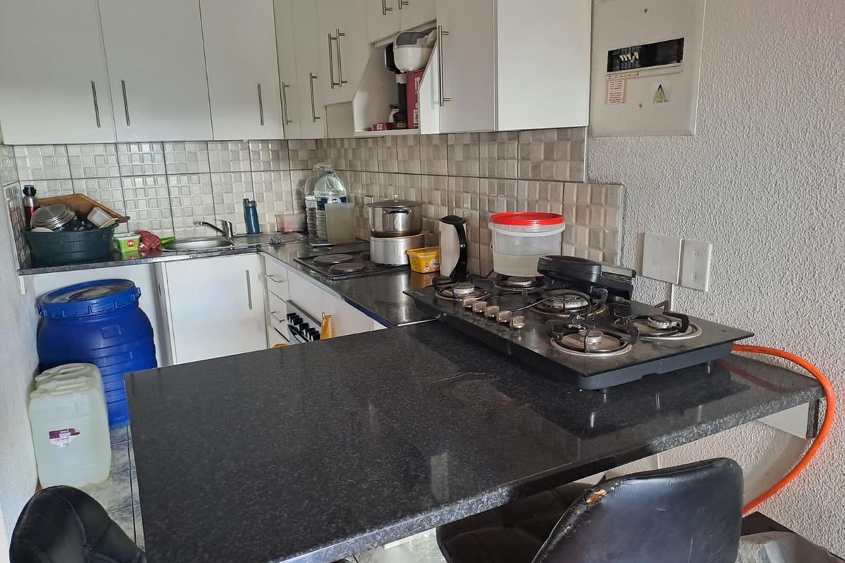 Compact kitchen featuring white cabinetry, dark granite countertops, a built-in gas hob, and a tiled backsplash.