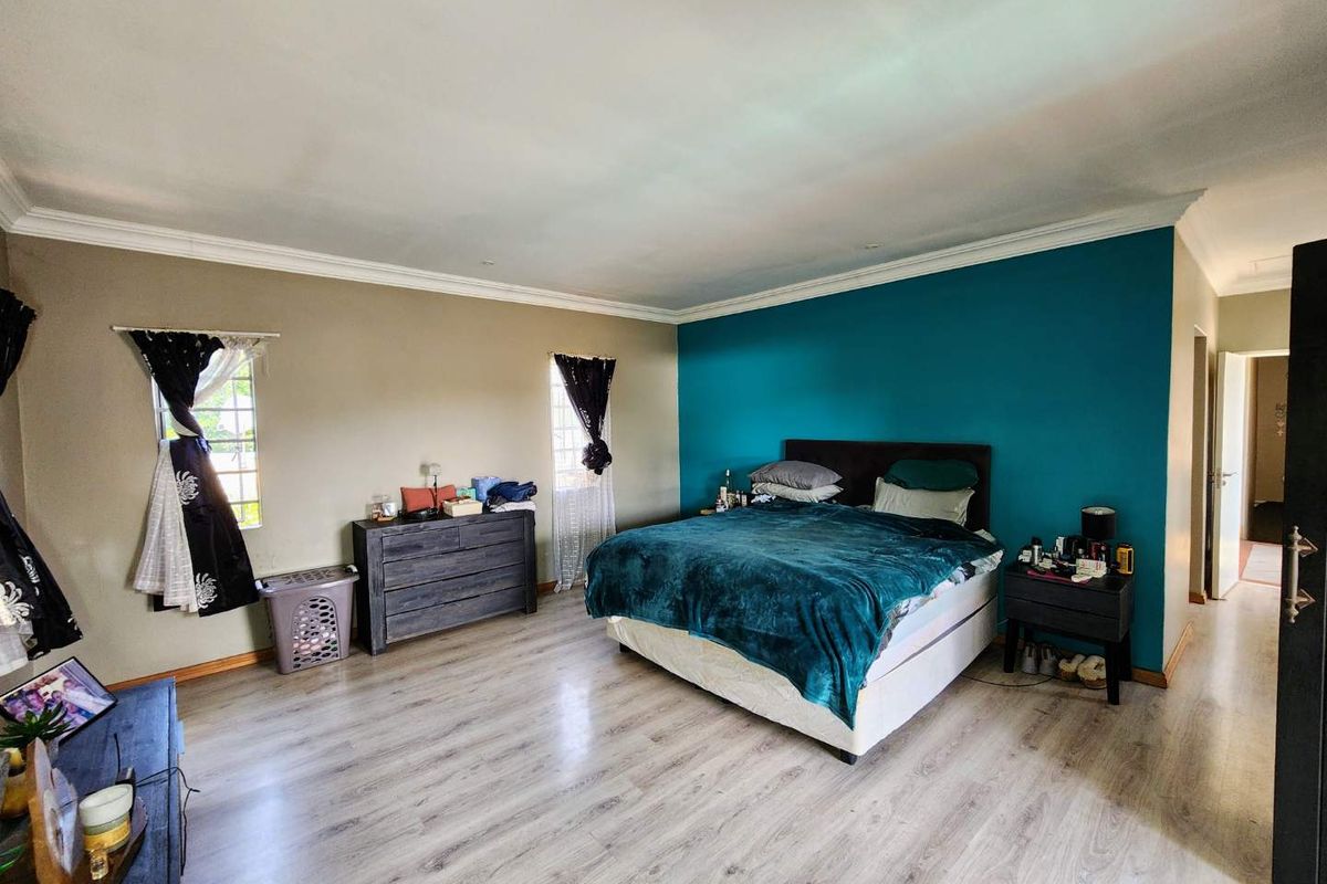Spacious bedroom featuring light-toned laminate flooring, decorative cove cornicing, and dual-aspect windows, providing a bright and functional living space.