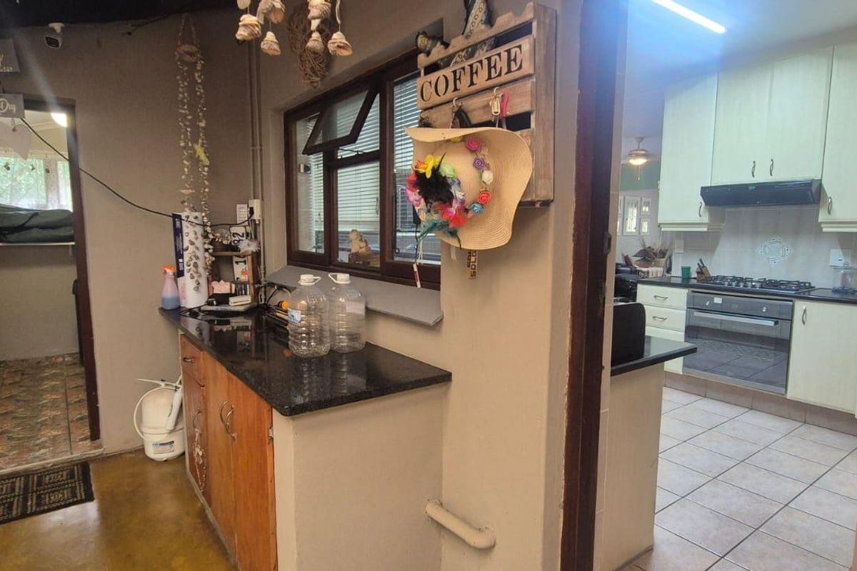 A functional kitchen area featuring built-in cabinetry, granite countertops, and integrated appliances, with an adjacent utility or laundry space visible.