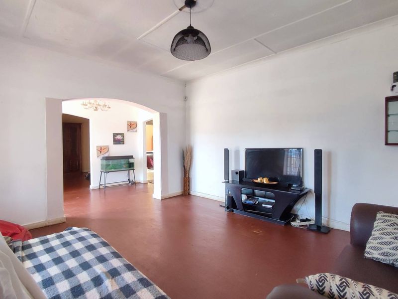 Spacious living room featuring an arched entryway, painted concrete flooring, and a central pendant light fixture.