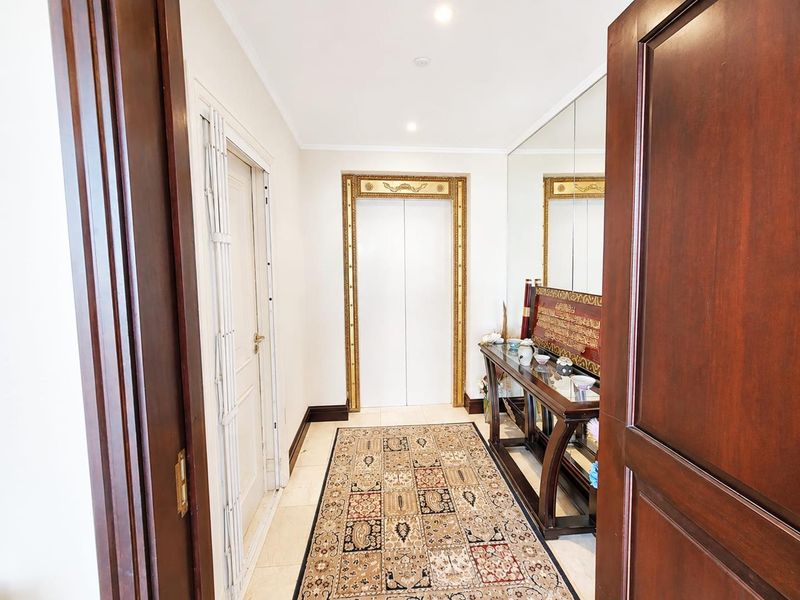 Private elevator entrance foyer featuring ornate gold detailing, full-height wall mirror, and polished tile flooring, providing a sophisticated welcome to the penthouse.